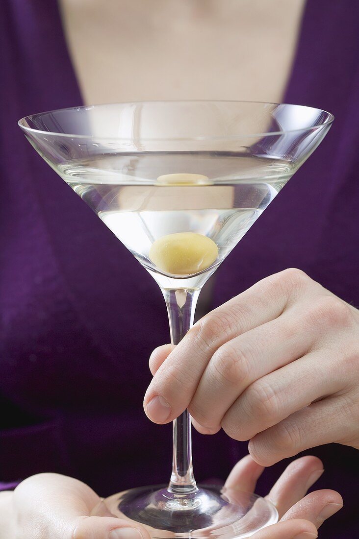 Frau hält Martini mit Olive