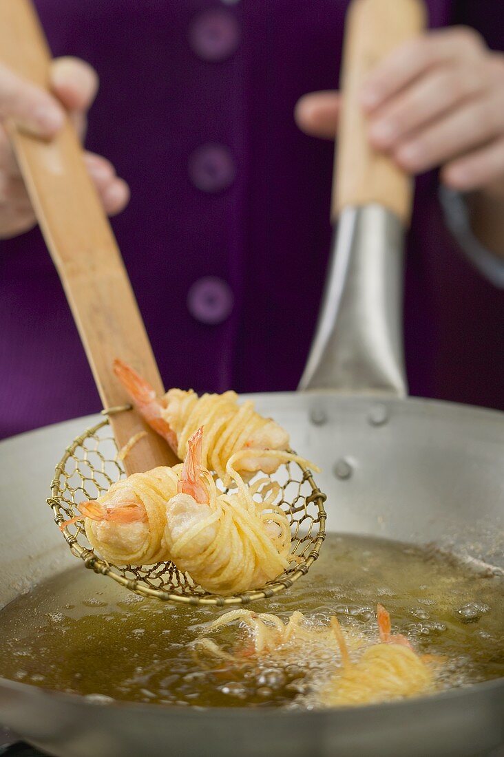 Deep-frying noodle-wrapped prawns in wok