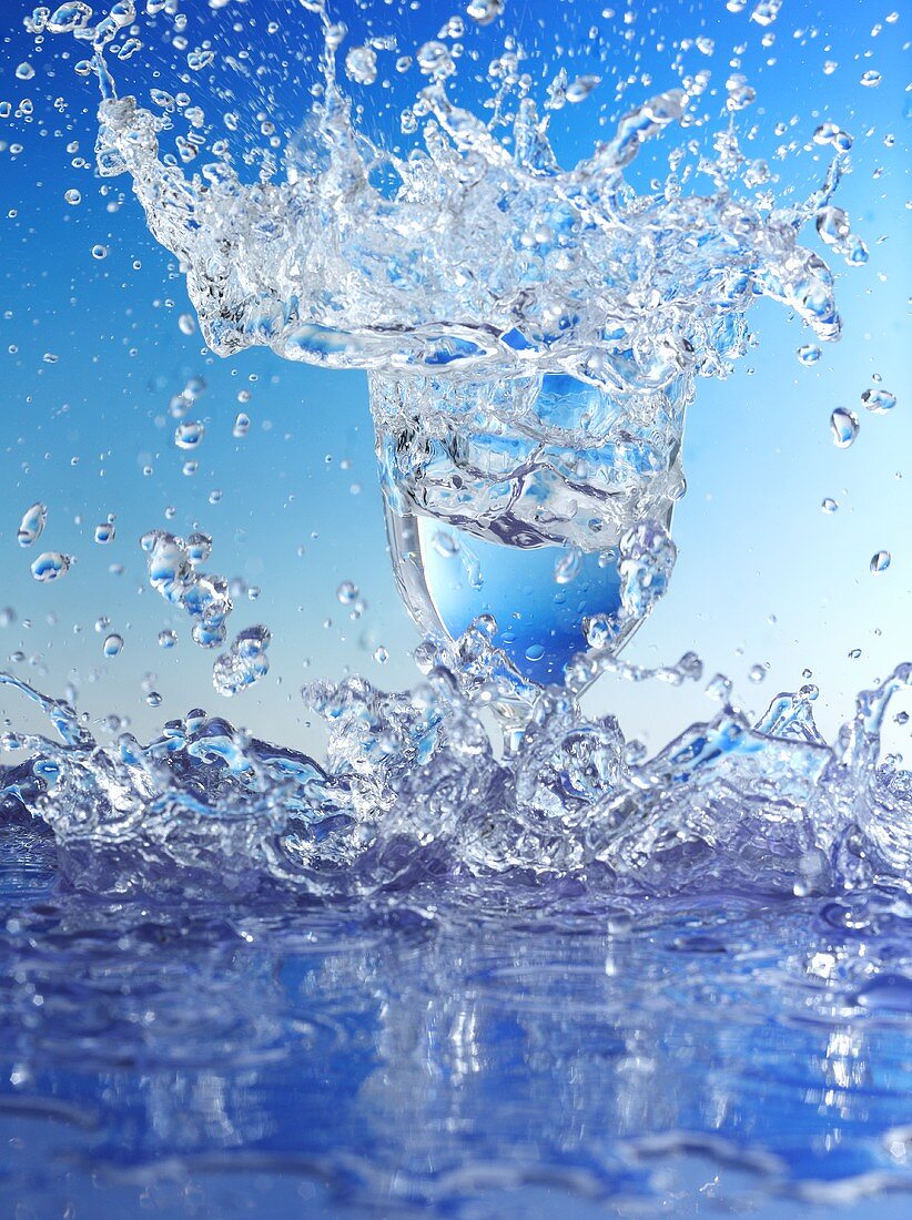 Blue water splashing out of glass