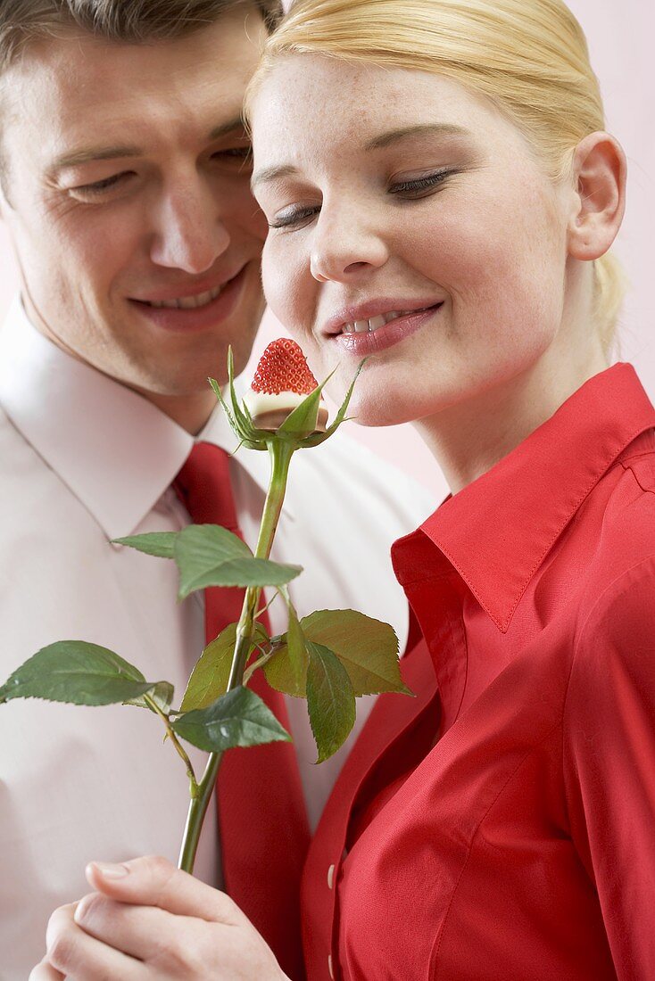 Romantisches Paar mit Schokoladenerdbeere auf Rosenstiel