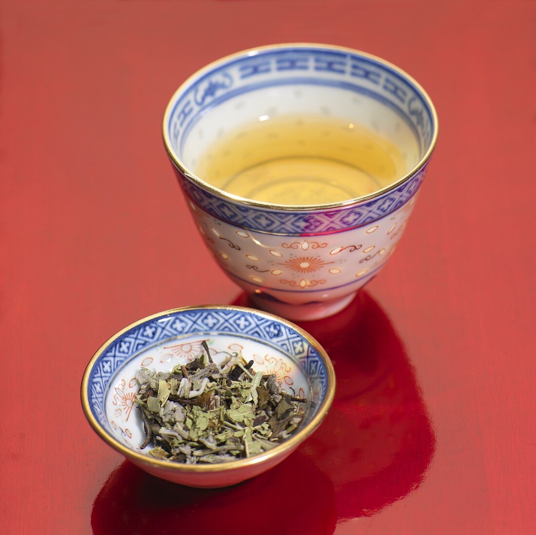 Green tea in bowl and tea leaves in small dish