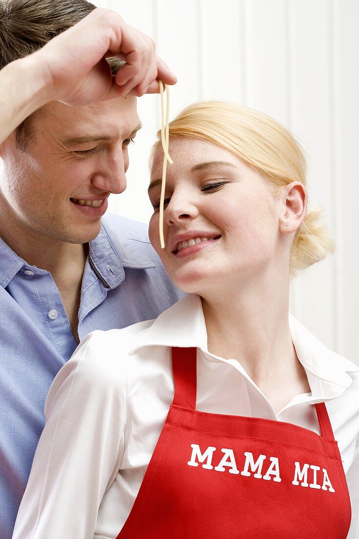 Mann hält Frau gekochte Spaghetti vors Gesicht