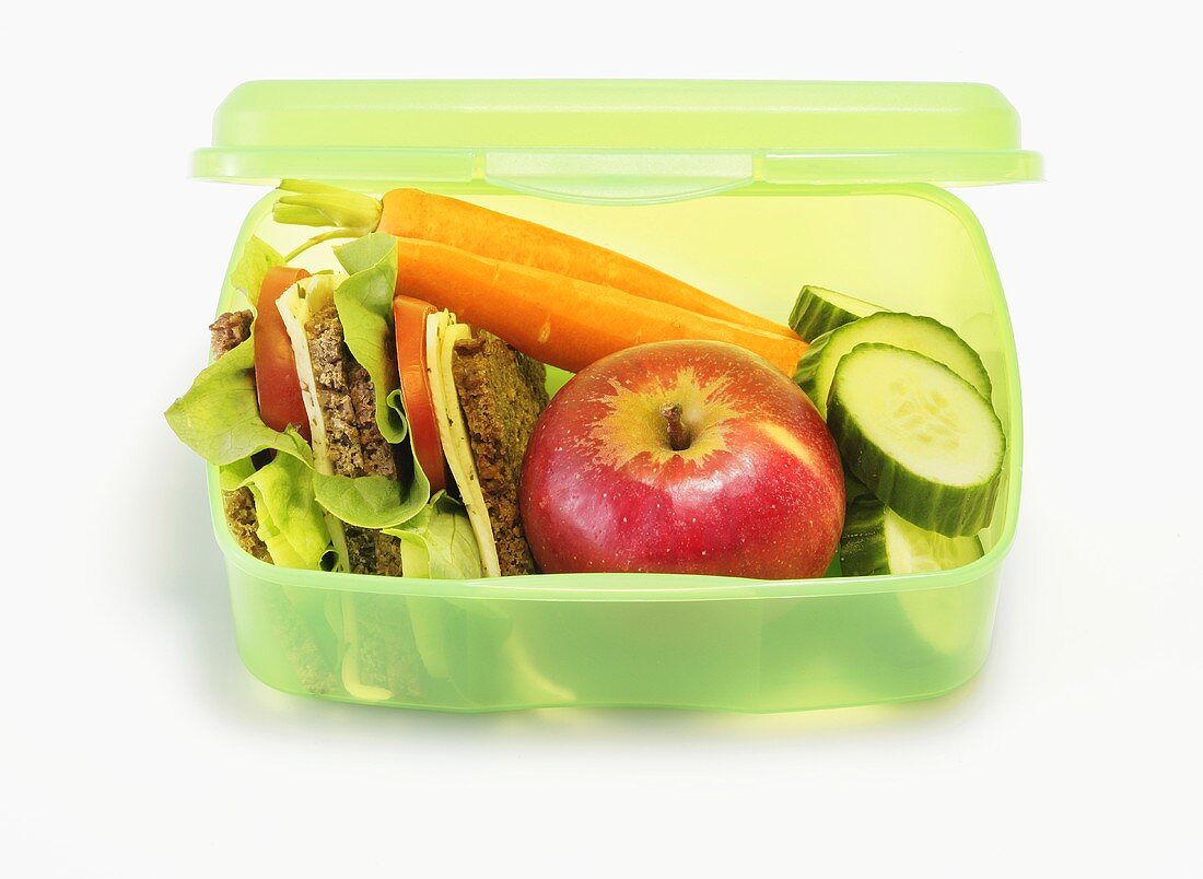 Healthy lunch box containing sandwiches, apples, vegetables
