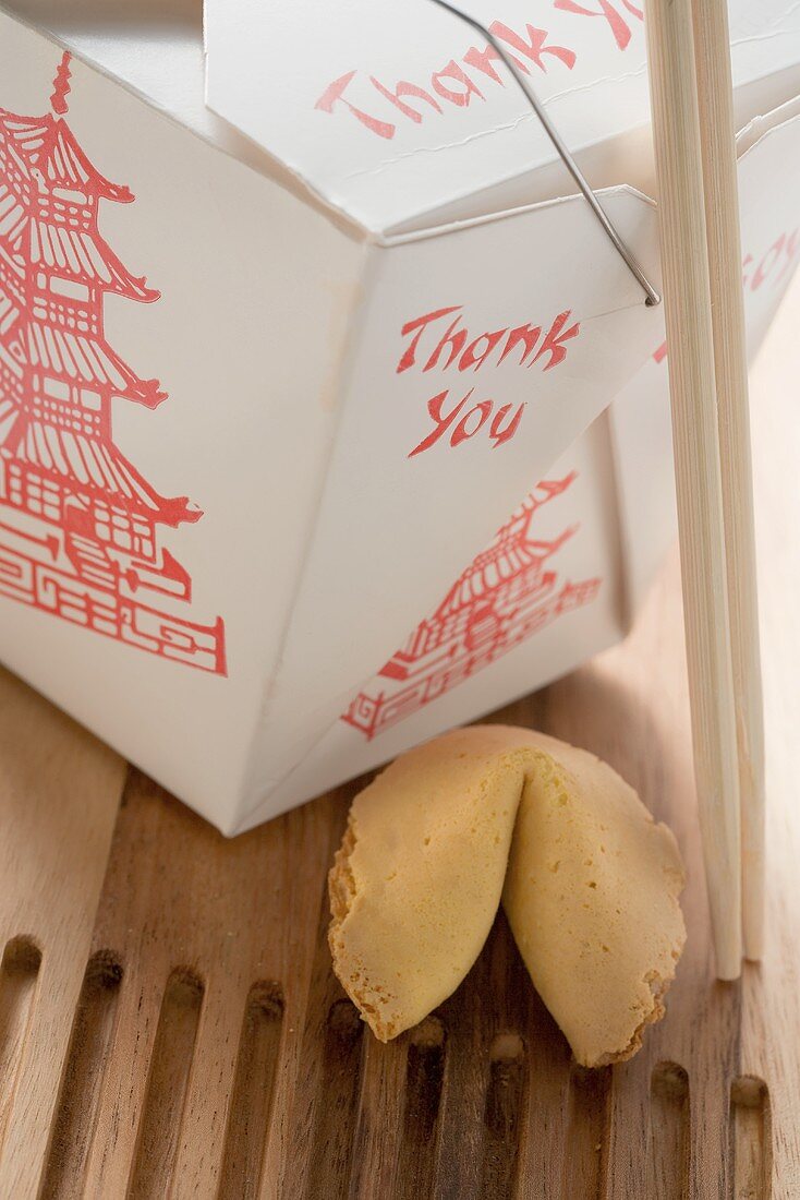 Asian snack in take-away box with chopsticks, fortune cookie