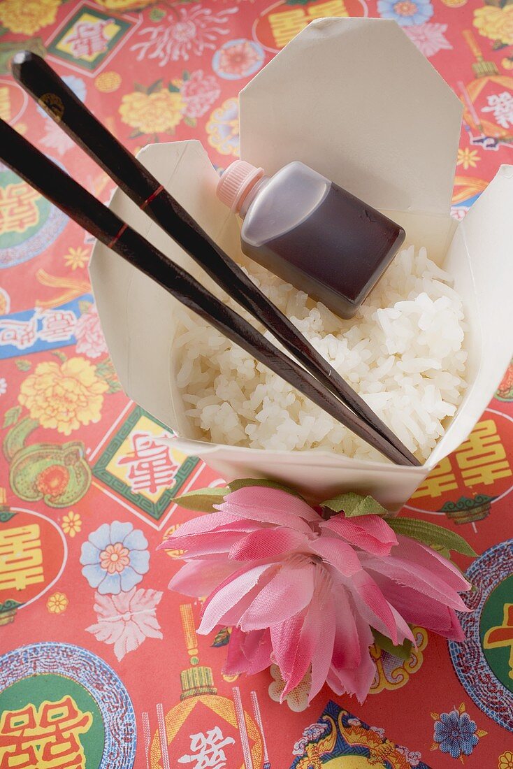 Reis, Sojasauce und Essstäbchen im Take-Out-Behälter