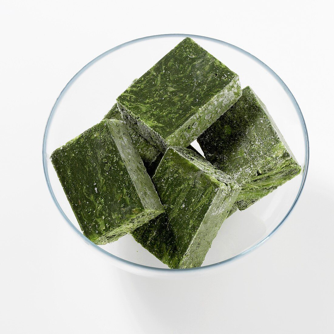 Cubes of frozen spinach in a glass bowl