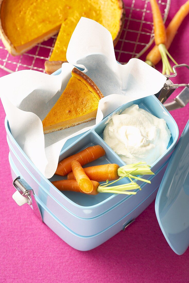 Carrot pie, cream and fresh carrots in lunch box