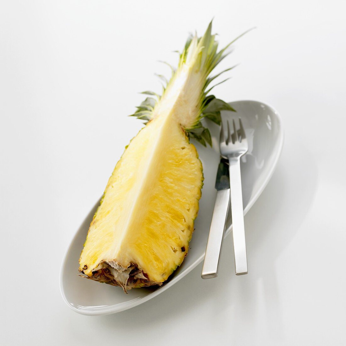 Pineapple quarter in dish with knife and fork