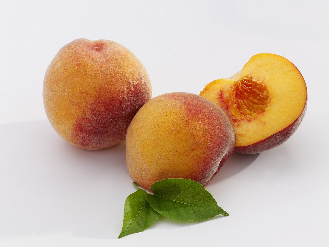 Peaches with leaves, whole and halved