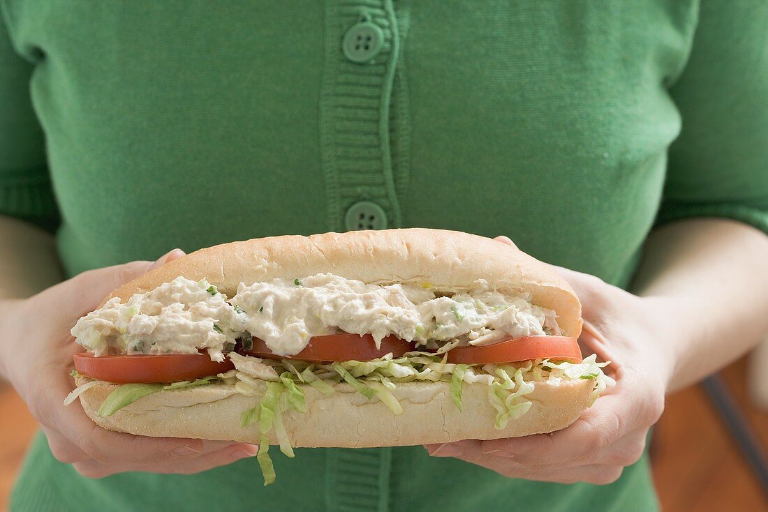 Frau hält Sandwich mit Hähnchensalat