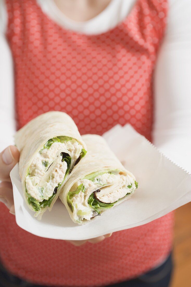 Frau hält zwei Thunfisch-Wraps auf Papier