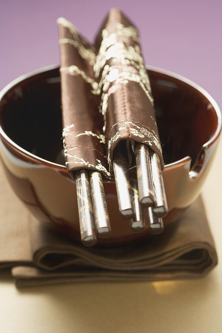 Lacquer bowl with chopsticks on brown cloth (Asia)