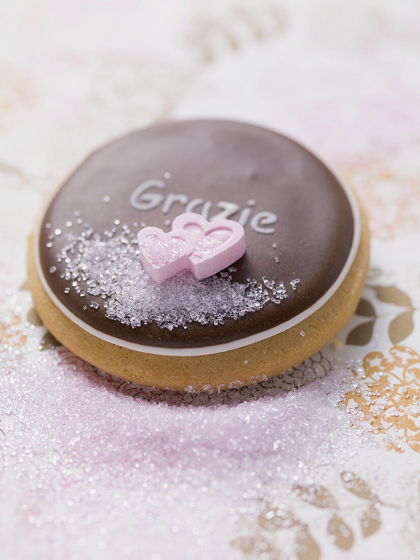 Biscuit with chocolate icing, sugar hearts & the word Grazie