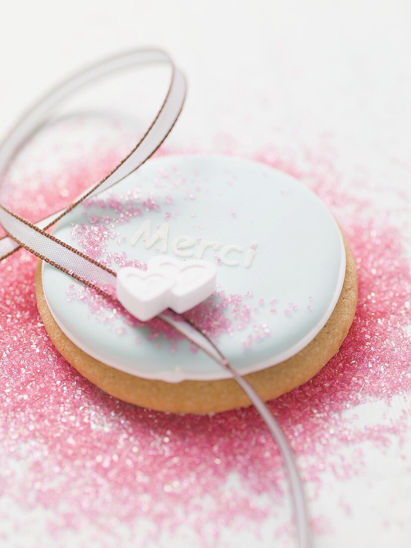 Biscuit with blue icing, sugar hearts and the word Merci