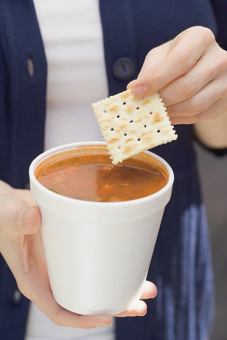 Woman holding tomato soup and cracker