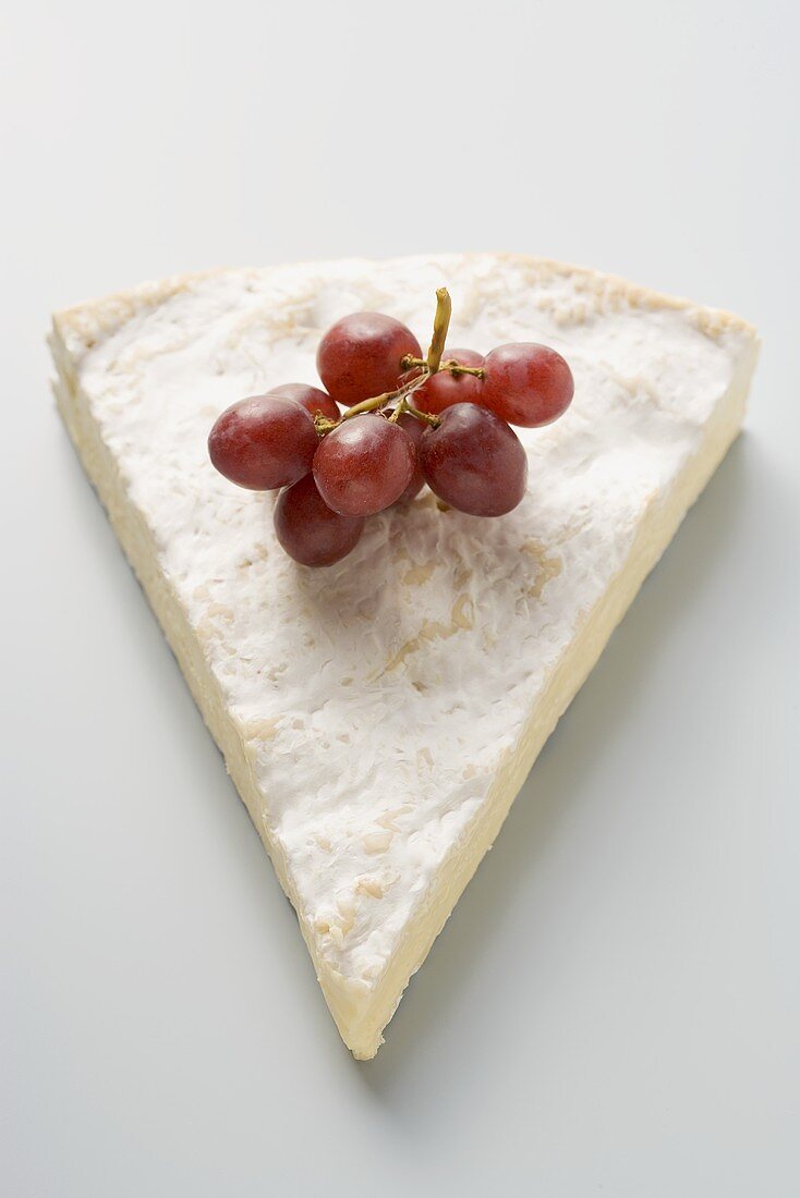 Stück Brie mit roten Trauben