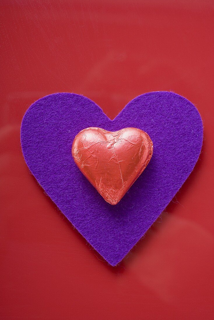 Red heart-shaped chocolate on purple felt heart