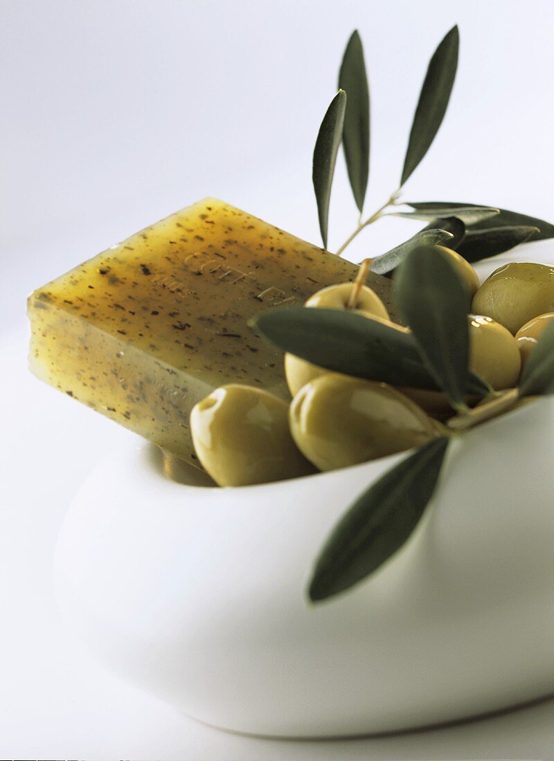 Olivenseife und grüne Oliven im Schälchen