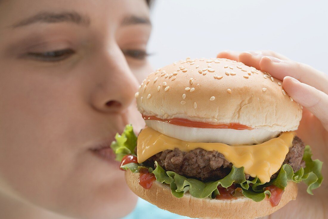 Junge Frau beisst in Cheeseburger