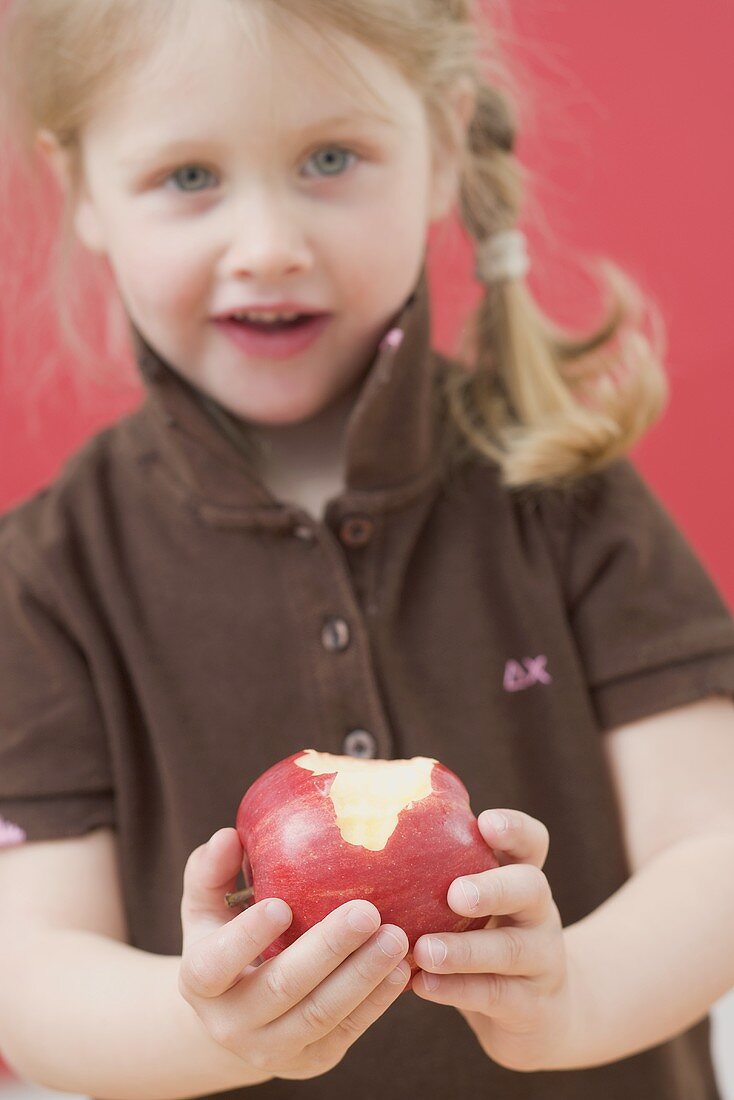 Little girl holding a partly eaten apple