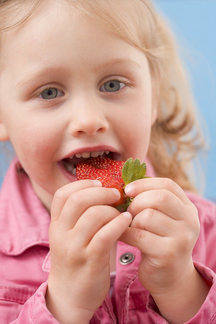 Little girl eating strawberry