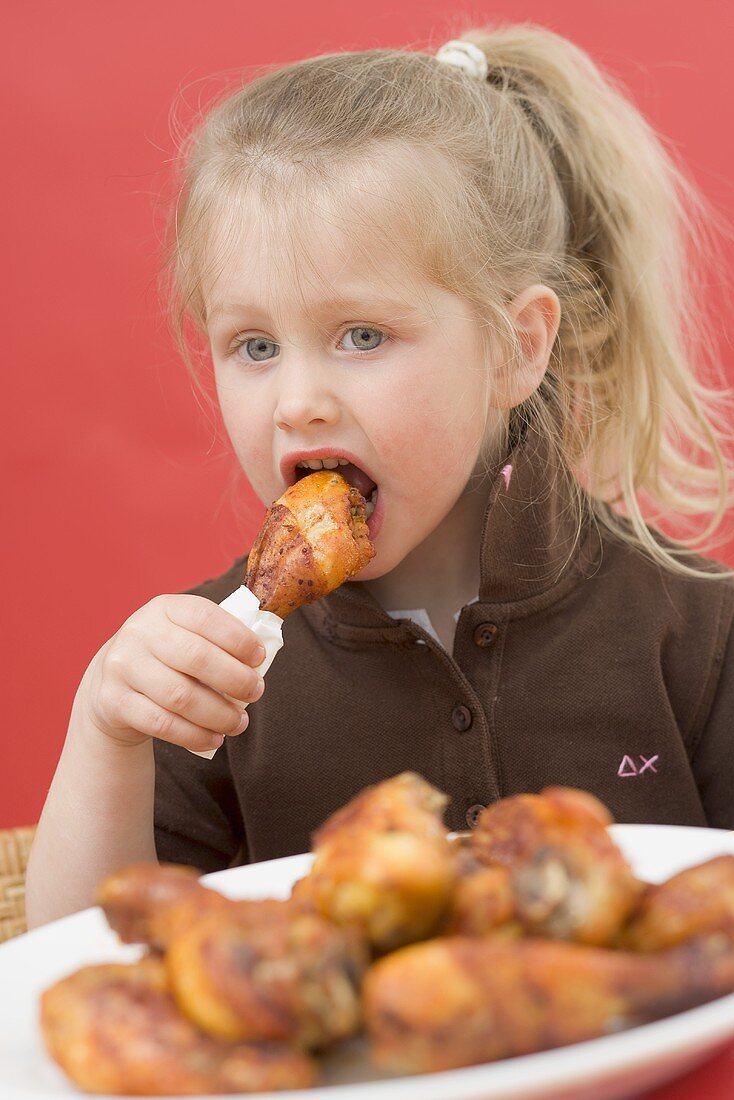 Kleines Mädchen isst Hähnchenkeule