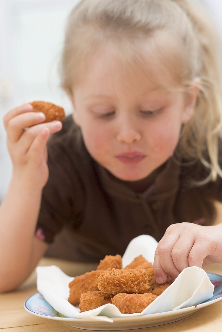 Kleines Mädchen isst Chicken Nuggets