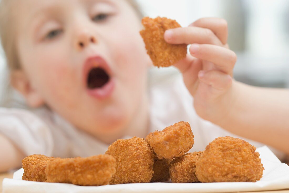 Kleines Mädchen isst Chicken Nuggets