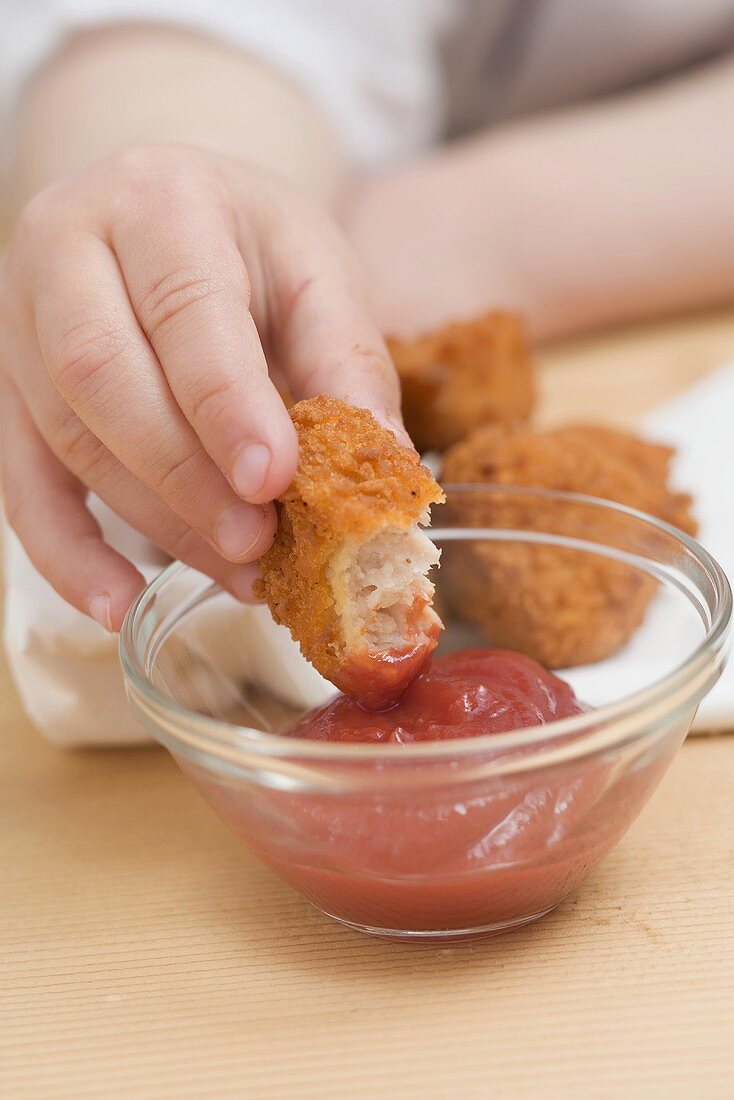 Kind dippt Chicken Nugget in Ketchup