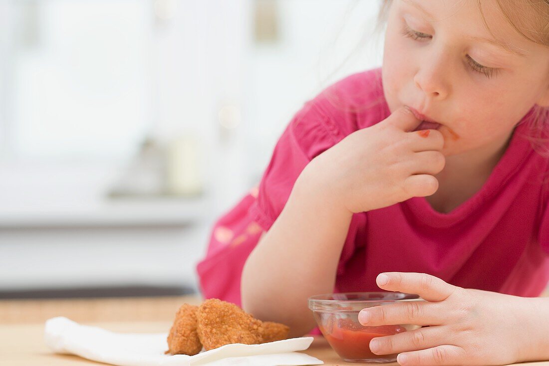 Kleines Mädchen isst Chicken Nuggets mit Ketchup