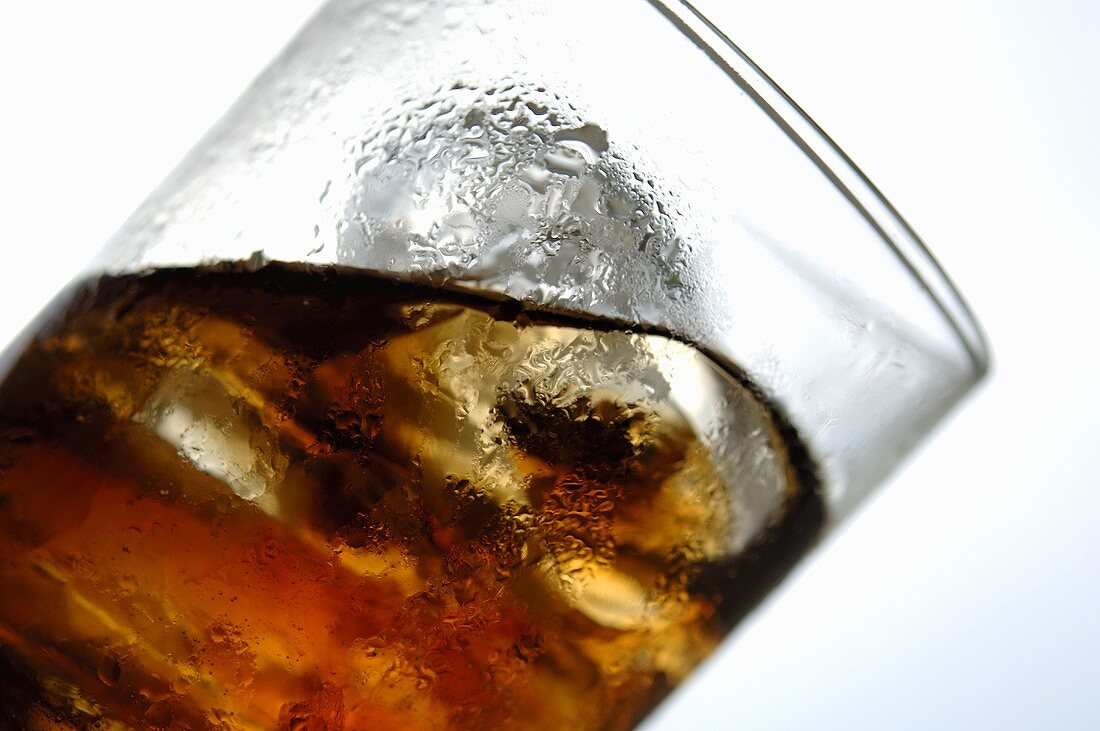 Cola with ice cubes in glass (tilted)