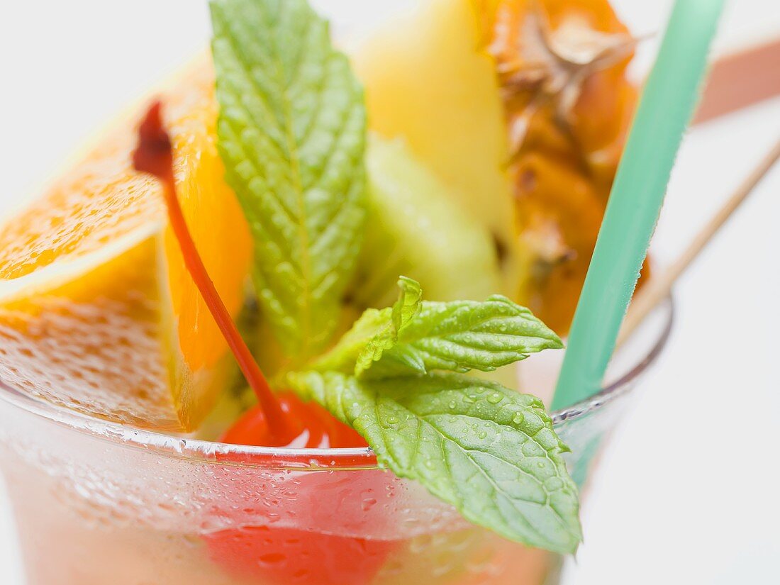 Cocktail with exotic fruit skewer and mint (close-up)