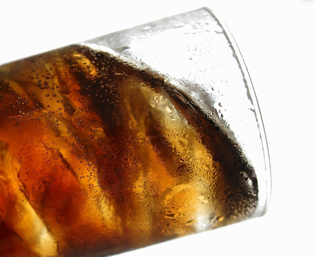 Cola mit Eiswürfeln im Glas (Schräglage)