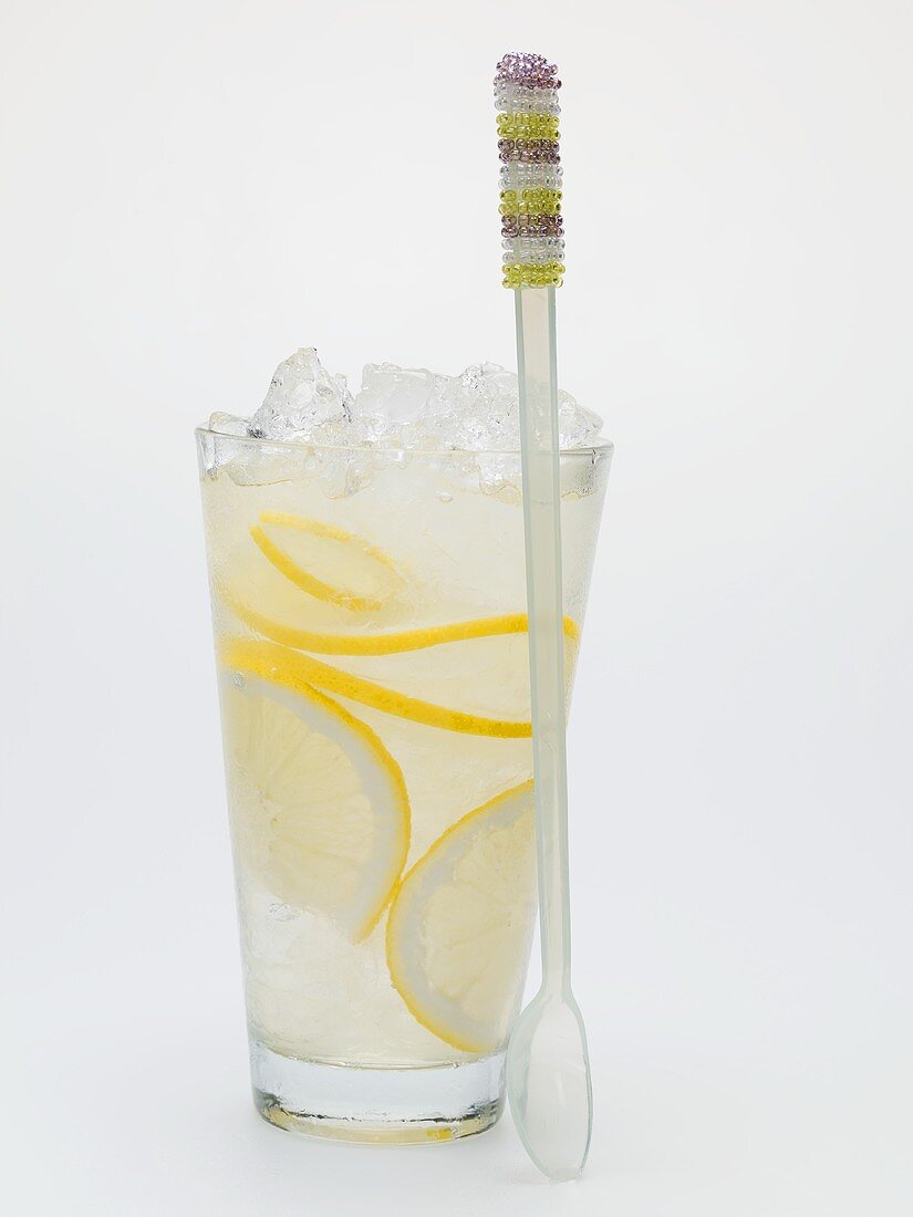 Ein Glas Zitronenlimonade mit Crushed Ice, daneben Löffel