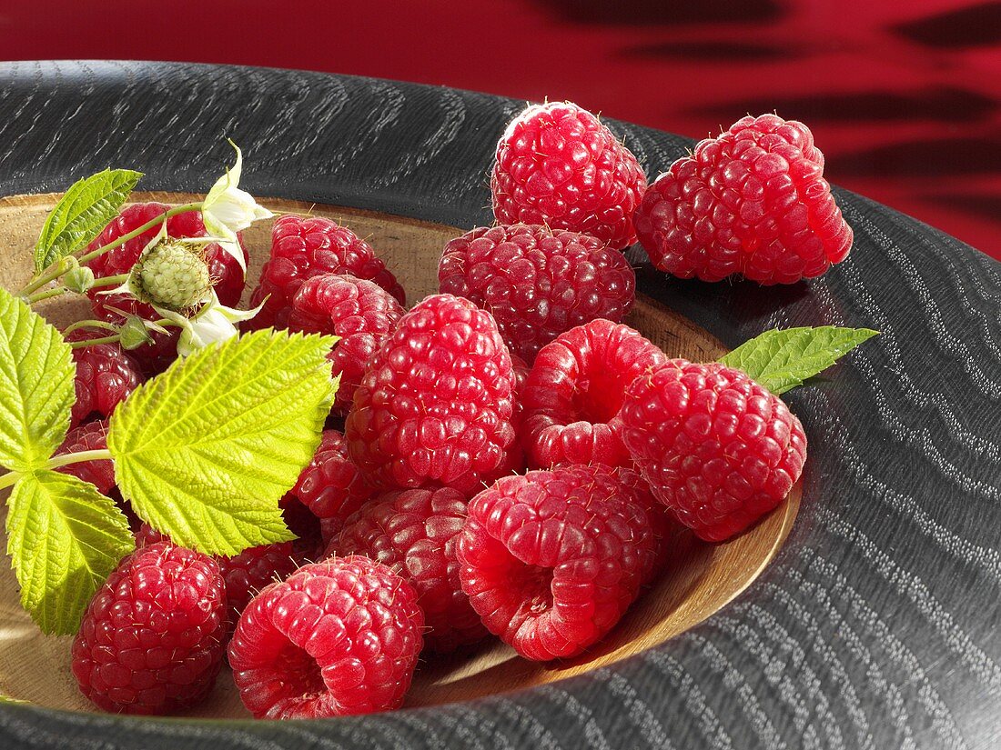Raspberries with leaf in wooden bowl