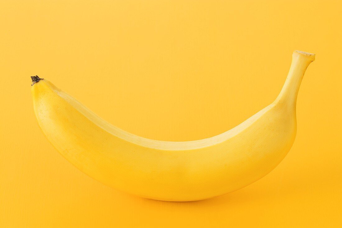 One banana on yellow background
