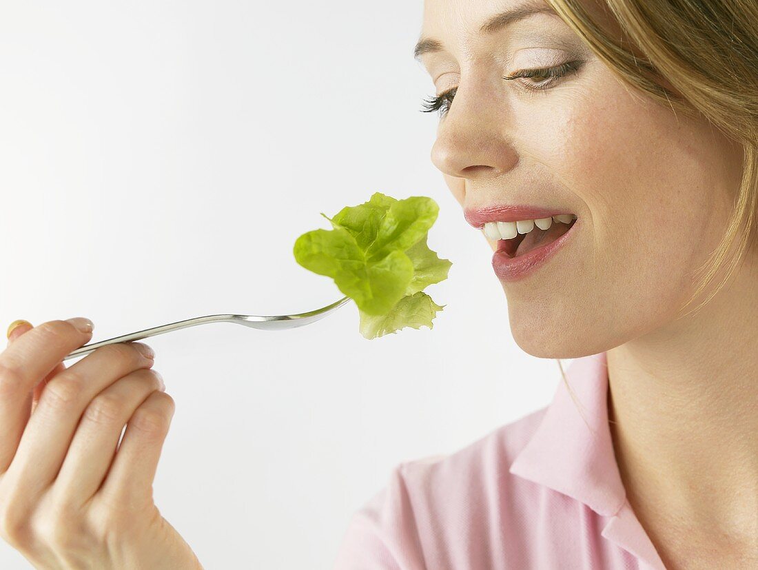 Woman holding lettuce leaf on fork