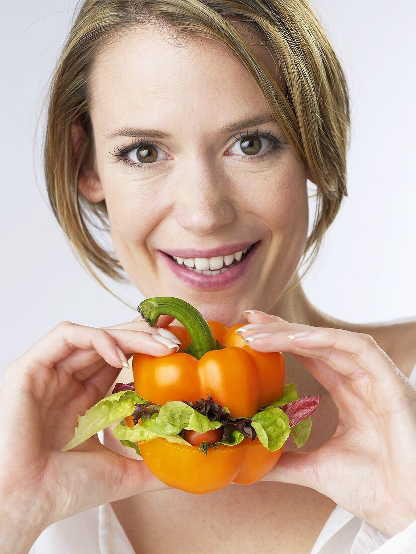 Woman holding a pepper filled with salad