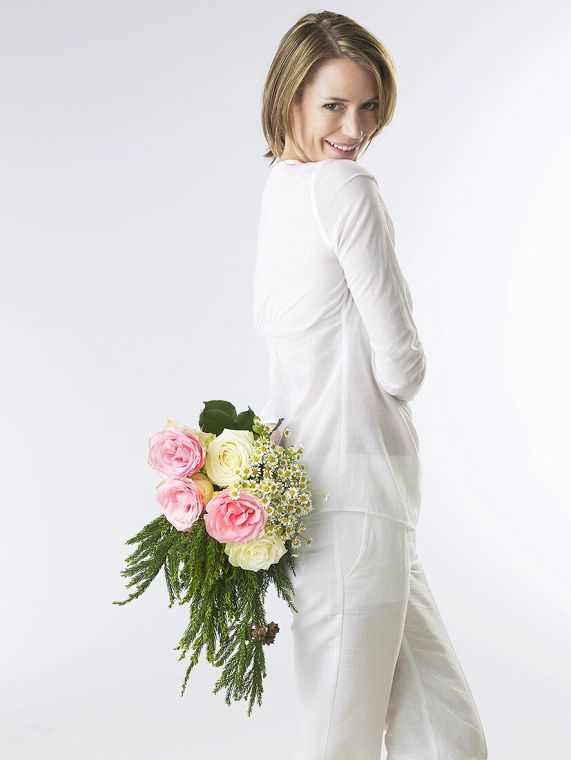 Woman holding a bouquet of flowers behind her back