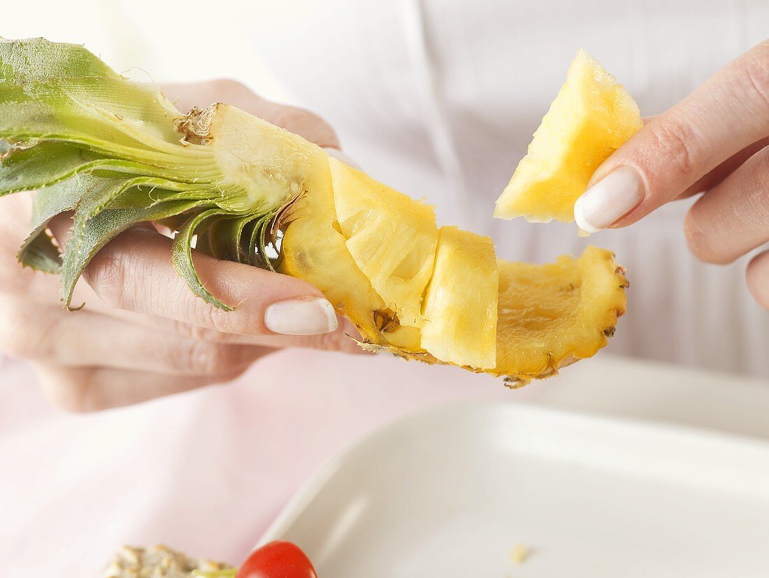 Hands holding a piece of pineapple