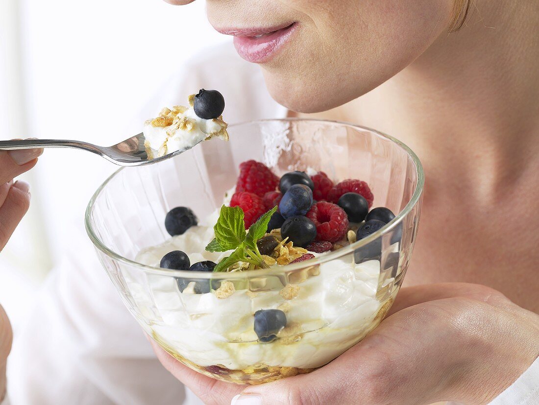 Woman eating yoghurt muesli with berries