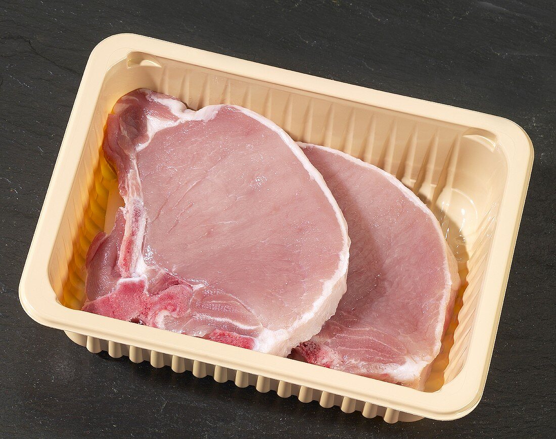Two pork chops in plastic container