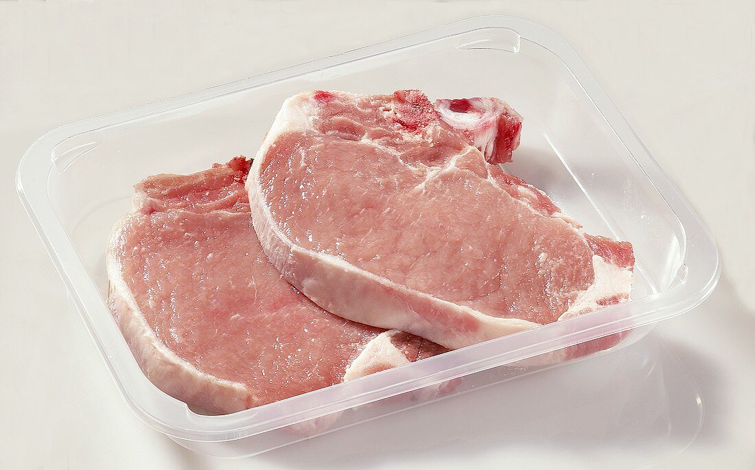 Two pork chops in plastic container