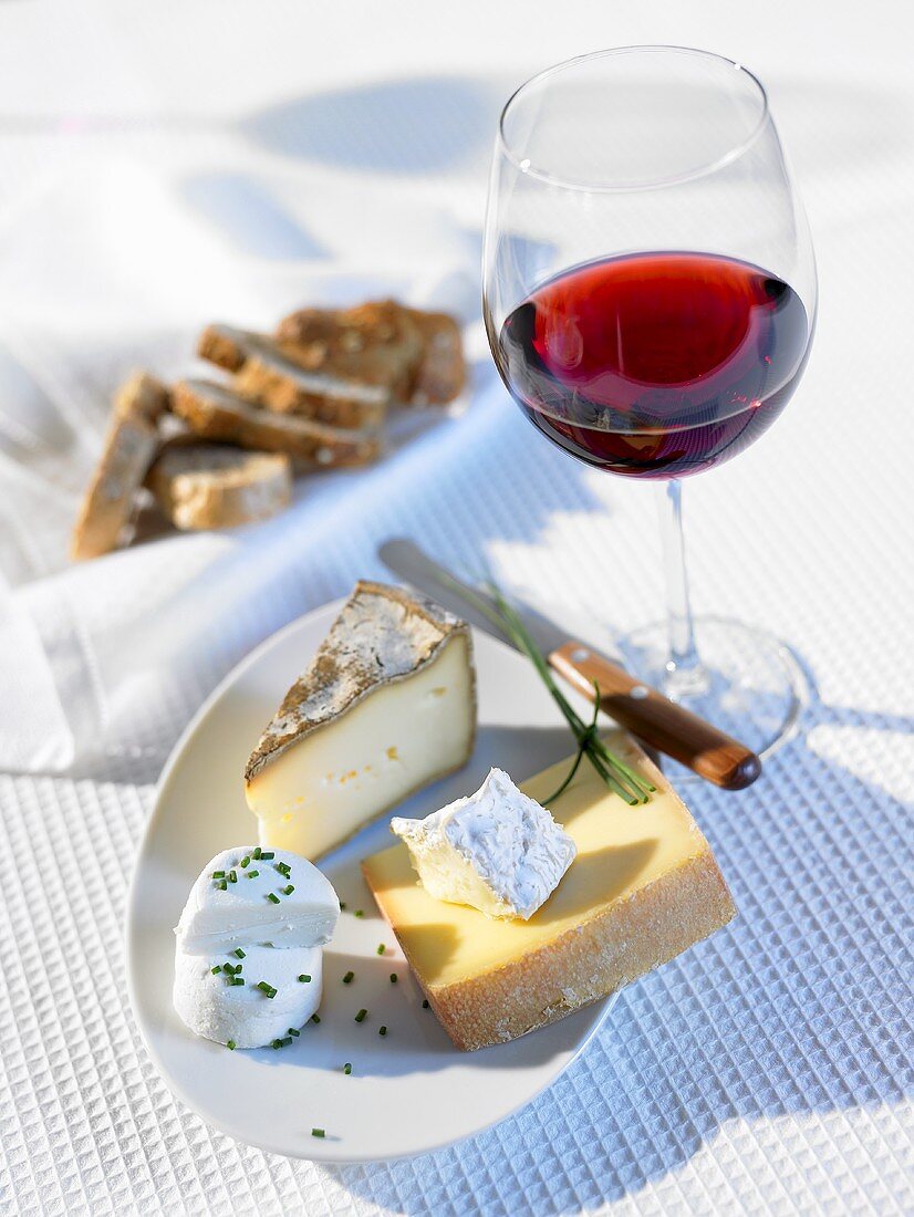 Käseplatte, Glas Rotwein und Brot