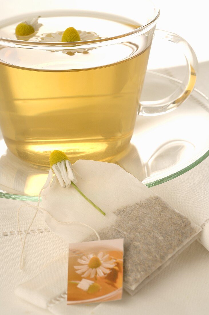 Chamomile tea in glass cup, tea bag, chamomile flowers