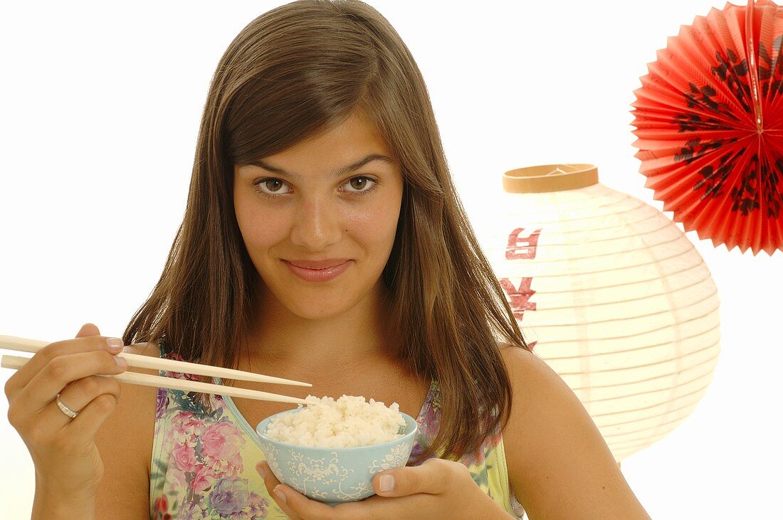 Junge Frau hält Schale Reis und Essstäbchen