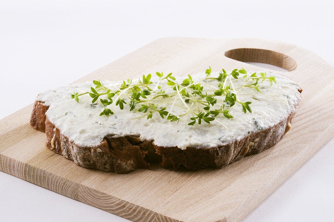 Quarkbrot mit frischer Kresse auf Schneidebrett