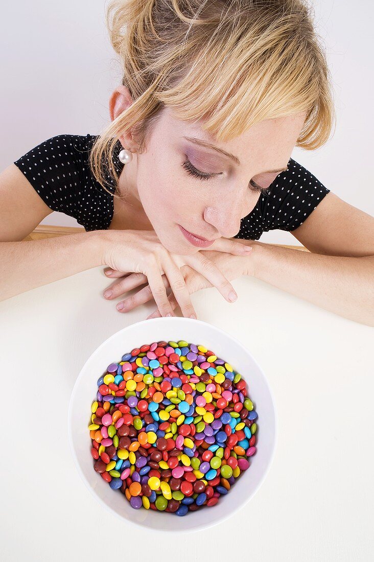 Woman looking pensively at coloured chocolate beans