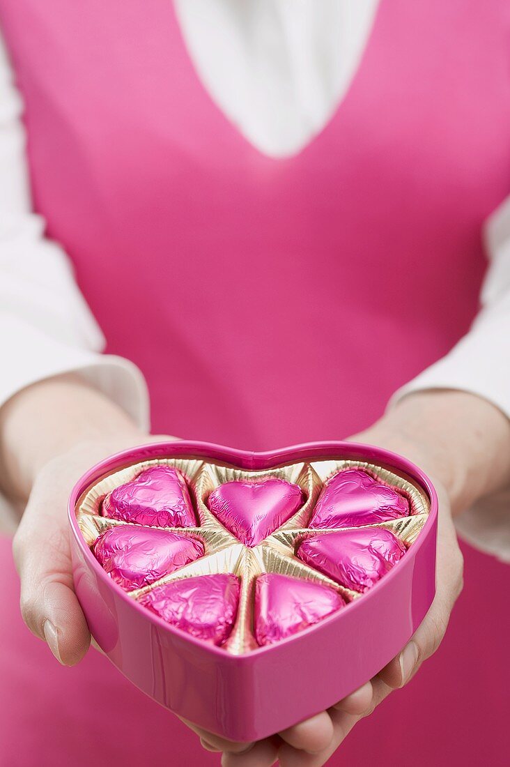 Woman holding box of heart-shaped chocolates