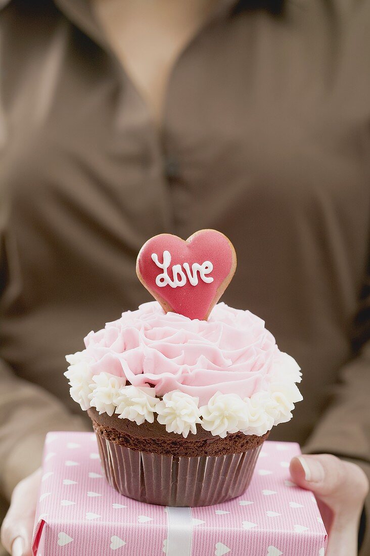 Frau hält Cupcake und Geschenk zum Valentinstag